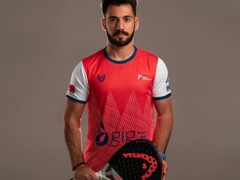 Man in a focused stance, preparing for a bodyweight squat in a spacious studio.